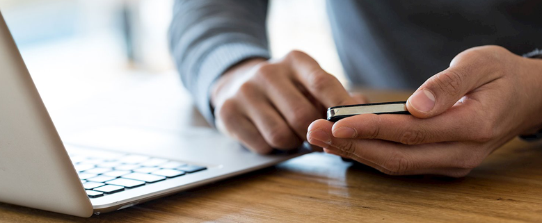 hombre con teléfono móvil y un portatil